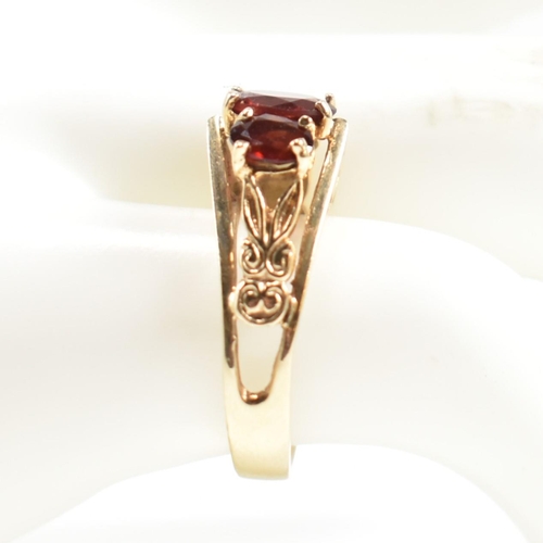 191 - A hallmarked 9ct gold and garnet trilogy ring. The ring set with three graduating four claw set oval... 