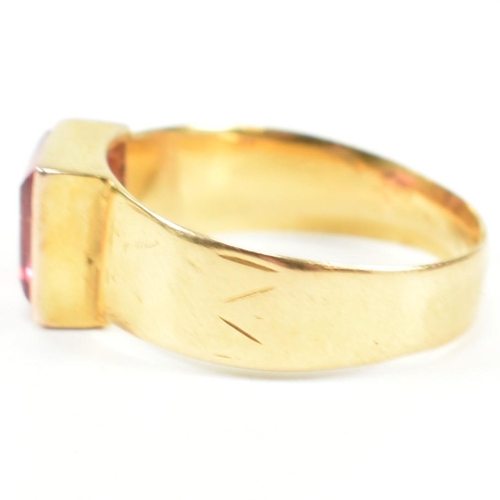 192 - A hallmarked 18ct gold and pink paste ring. The ring set with a single bezel set baguette cut pink p... 