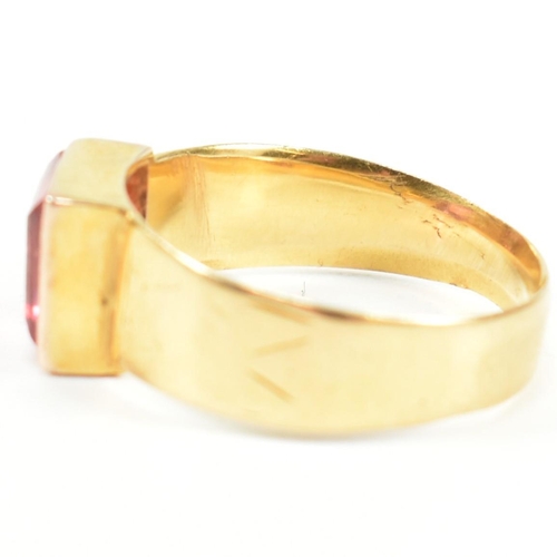 192 - A hallmarked 18ct gold and pink paste ring. The ring set with a single bezel set baguette cut pink p... 