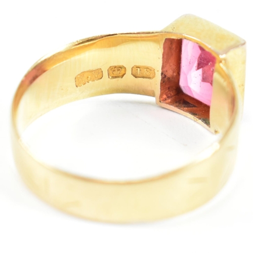 192 - A hallmarked 18ct gold and pink paste ring. The ring set with a single bezel set baguette cut pink p... 