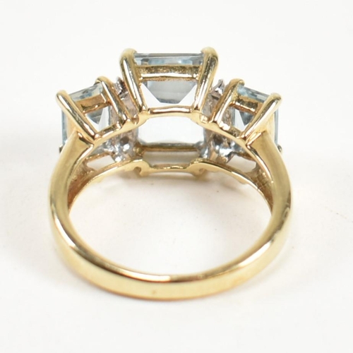 194 - A hallmarked 9ct gold aquamarine and diamond trilogy ring. The ring set with a central four claw set... 