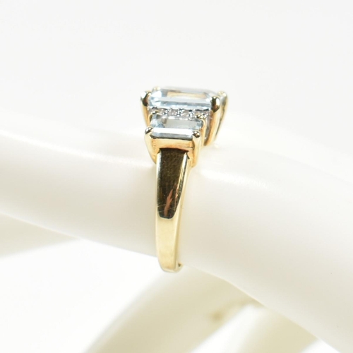 194 - A hallmarked 9ct gold aquamarine and diamond trilogy ring. The ring set with a central four claw set... 