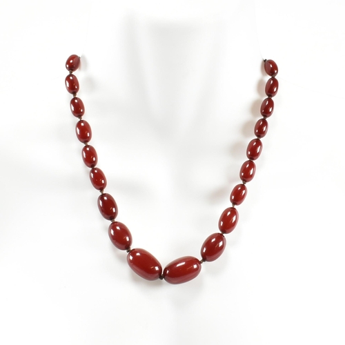 21 - A cherry amber Bakelite bead necklace. The beads measuring from 12mm to largest approximately 2.7cm.... 