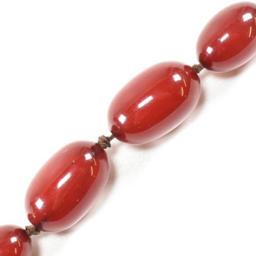 21 - A cherry amber Bakelite bead necklace. The beads measuring from 12mm to largest approximately 2.7cm.... 