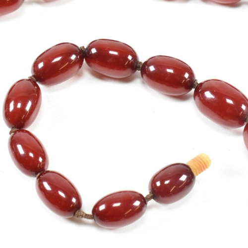 21 - A cherry amber Bakelite bead necklace. The beads measuring from 12mm to largest approximately 2.7cm.... 