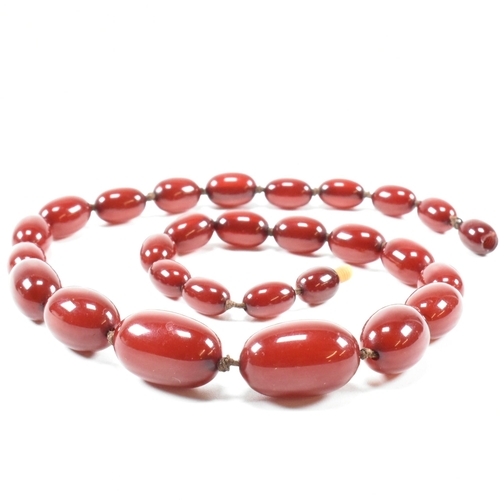 21 - A cherry amber Bakelite bead necklace. The beads measuring from 12mm to largest approximately 2.7cm.... 