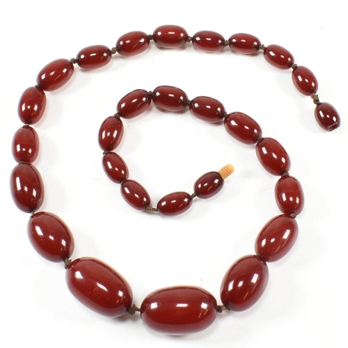 21 - A cherry amber Bakelite bead necklace. The beads measuring from 12mm to largest approximately 2.7cm.... 