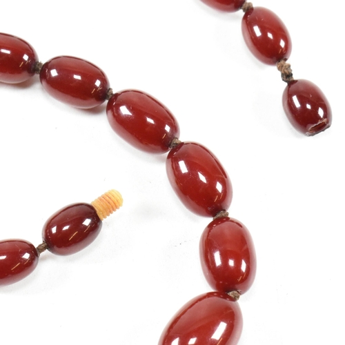 21 - A cherry amber Bakelite bead necklace. The beads measuring from 12mm to largest approximately 2.7cm.... 