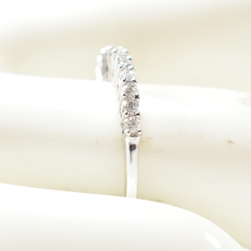 212 - A hallmarked 9ct white gold and diamond half hoop ring. The ring having a single row of eleven round... 