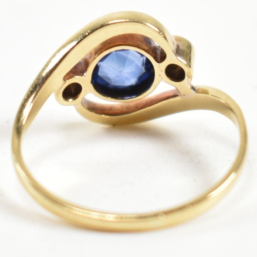 216 - An 18ct gold, sapphire and diamond cross over ring. The ring having a central bezel set sapphire wit... 