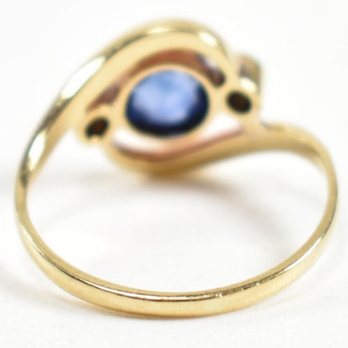 216 - An 18ct gold, sapphire and diamond cross over ring. The ring having a central bezel set sapphire wit... 