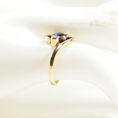 216 - An 18ct gold, sapphire and diamond cross over ring. The ring having a central bezel set sapphire wit... 