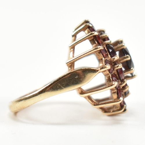 221 - A hallmarked 9ct gold and garnet cluster ring. The ring set with a central round cut garnet surround... 