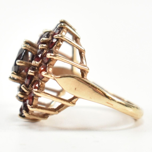 221 - A hallmarked 9ct gold and garnet cluster ring. The ring set with a central round cut garnet surround... 