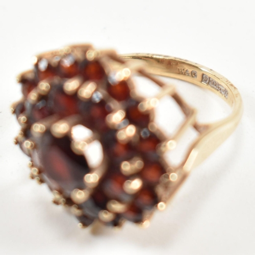 221 - A hallmarked 9ct gold and garnet cluster ring. The ring set with a central round cut garnet surround... 