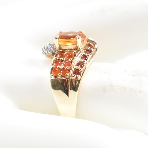 234 - A hallmarked diamond and gem set crossover ring. The ring having a central oval cut citrine set in a... 