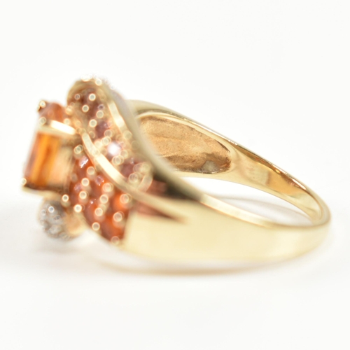 234 - A hallmarked diamond and gem set crossover ring. The ring having a central oval cut citrine set in a... 