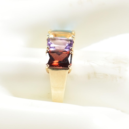 235 - A hallmarked 9ct gold, garnet, amethyst, citrine and topaz ring. The ring set with a row of emerald ... 