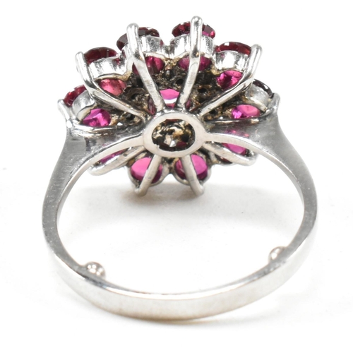 237 - A white gold ruby and diamond cluster ring. The ring set with round cut rubies and single cut diamon... 