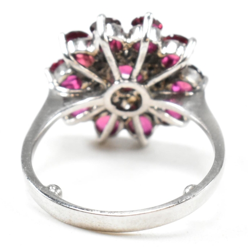 237 - A white gold ruby and diamond cluster ring. The ring set with round cut rubies and single cut diamon... 