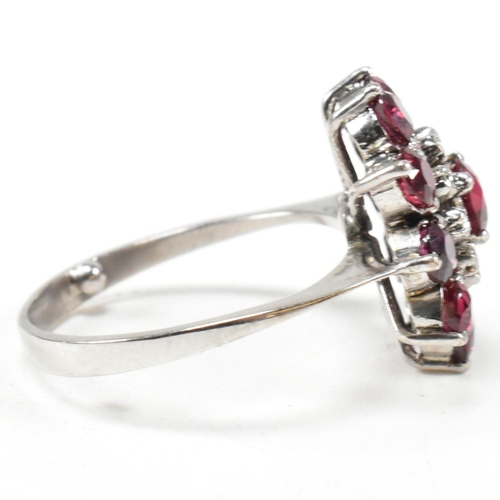 237 - A white gold ruby and diamond cluster ring. The ring set with round cut rubies and single cut diamon... 