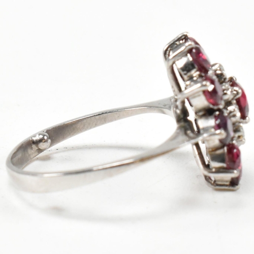 237 - A white gold ruby and diamond cluster ring. The ring set with round cut rubies and single cut diamon... 