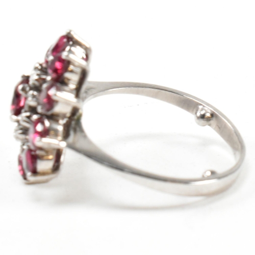 237 - A white gold ruby and diamond cluster ring. The ring set with round cut rubies and single cut diamon... 