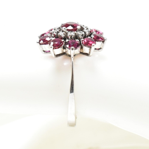 237 - A white gold ruby and diamond cluster ring. The ring set with round cut rubies and single cut diamon... 