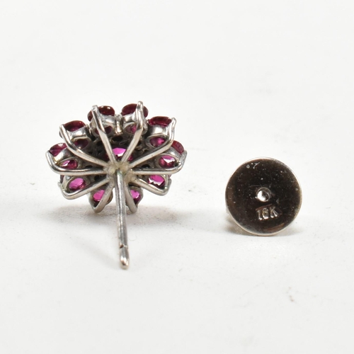 238 - A pair of white gold ruby and diamond cluster earrings. The earrings set set with round cut rubies a... 