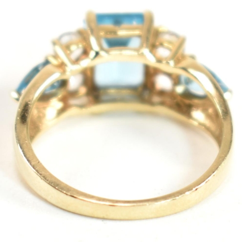 239 - A hallmarked 9ct gold, blue topaz and white topaz ring. The ring set with a central emerald cut blue... 