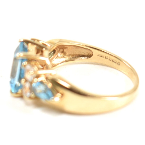 239 - A hallmarked 9ct gold, blue topaz and white topaz ring. The ring set with a central emerald cut blue... 