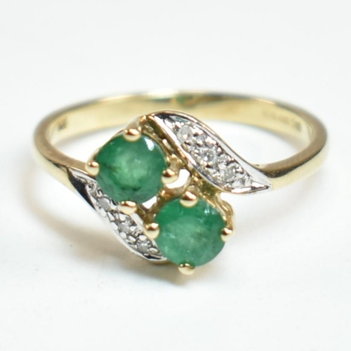 279 - A hallmarked 9ct gold, emerald and diamond crossover ring. The ring set with two four claw round cut... 