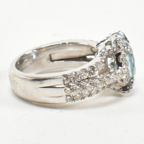 280 - An 18ct white gold, aquamarine and diamond cluster ring. The ring set with a central round mixed cut... 