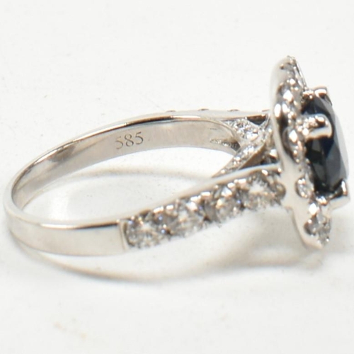 291 - A 14ct white gold, sapphire and diamond halo ring. The ring set with a central round mixed cut sapph... 