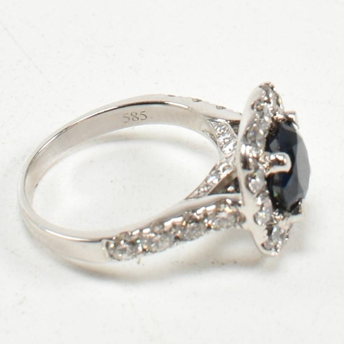 291 - A 14ct white gold, sapphire and diamond halo ring. The ring set with a central round mixed cut sapph... 