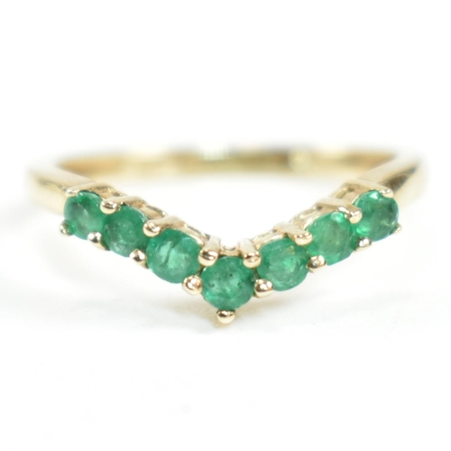 292 - A hallmarked 9ct gold and emerald wishbone ring. The ring set with a single row of shared claw round... 