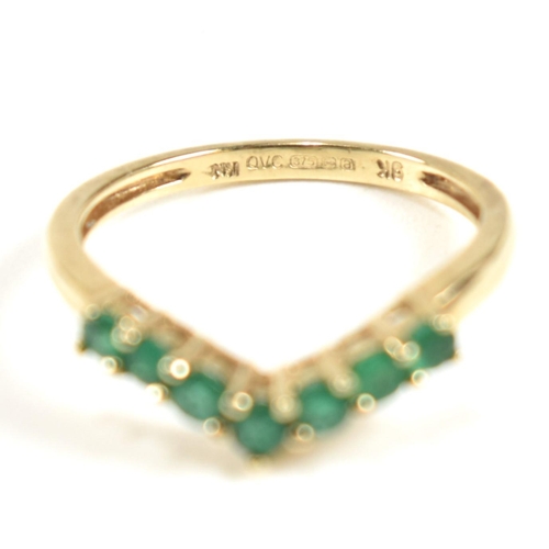 292 - A hallmarked 9ct gold and emerald wishbone ring. The ring set with a single row of shared claw round... 