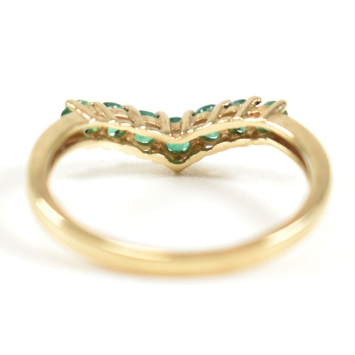 292 - A hallmarked 9ct gold and emerald wishbone ring. The ring set with a single row of shared claw round... 