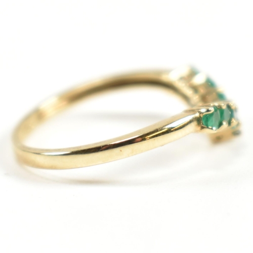 292 - A hallmarked 9ct gold and emerald wishbone ring. The ring set with a single row of shared claw round... 