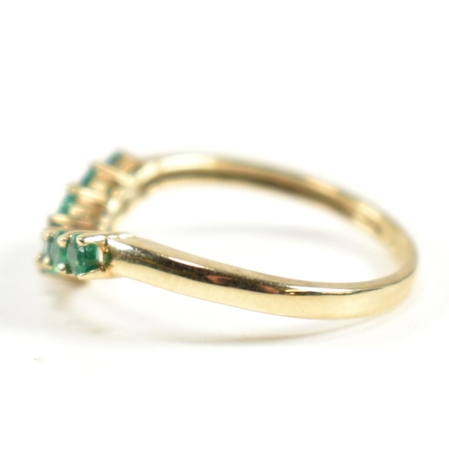 292 - A hallmarked 9ct gold and emerald wishbone ring. The ring set with a single row of shared claw round... 