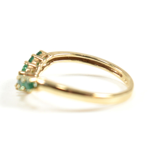 292 - A hallmarked 9ct gold and emerald wishbone ring. The ring set with a single row of shared claw round... 