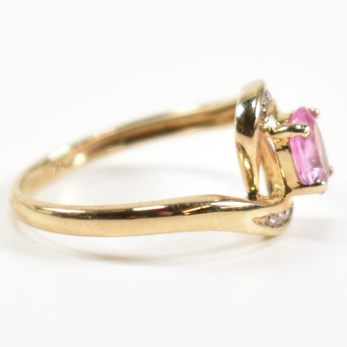 296 - A hallmarked 9ct gold, pink sapphire and diamond crossover ring. The ring set with a central four cl... 