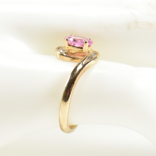 296 - A hallmarked 9ct gold, pink sapphire and diamond crossover ring. The ring set with a central four cl... 