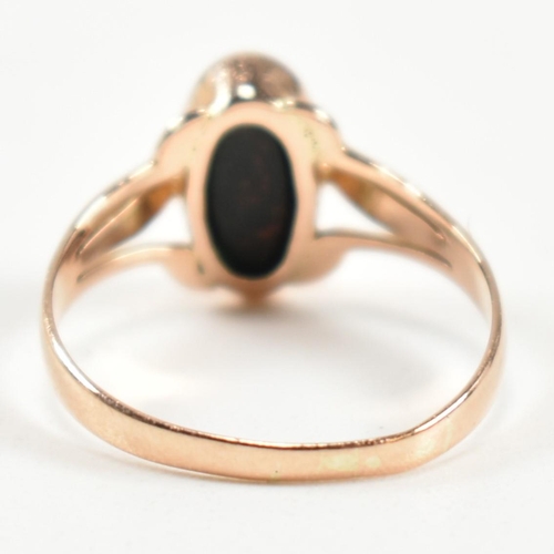 299 - A gold and bloodstone ring. The ring set with a bezel set oval cut bloodstone to pierced shoulders. ... 