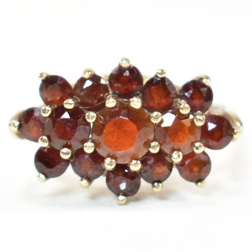 322 - A hallmarked 9ct gold and garnet cluster ring. The ring set with three central graduating round cut ... 