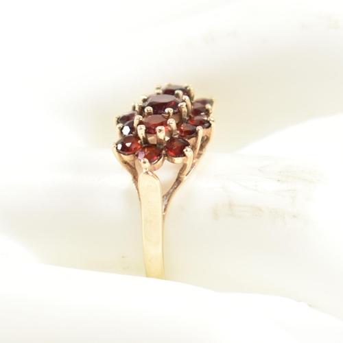 322 - A hallmarked 9ct gold and garnet cluster ring. The ring set with three central graduating round cut ... 