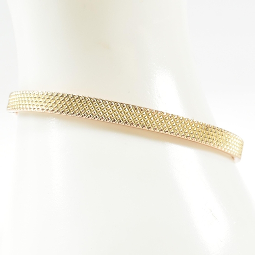 324 - A vintage hallmarked 9ct gold hinged bangle. The bangle having a textured pineapple decoration to he... 