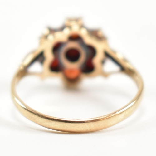 332 - A hallmarked 9ct gold and garnet cluster ring. The ring having central six claw set round cut garnet... 