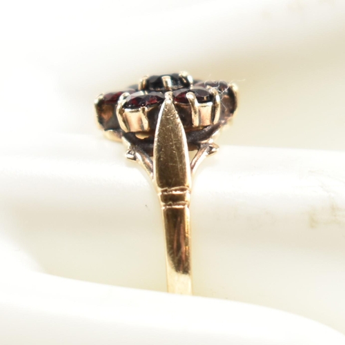 332 - A hallmarked 9ct gold and garnet cluster ring. The ring having central six claw set round cut garnet... 