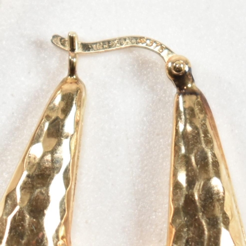 335 - A pair of hallmarked 9ct gold hammered hoop earrings. The arrow-shape hoop earrings having an all-ov... 